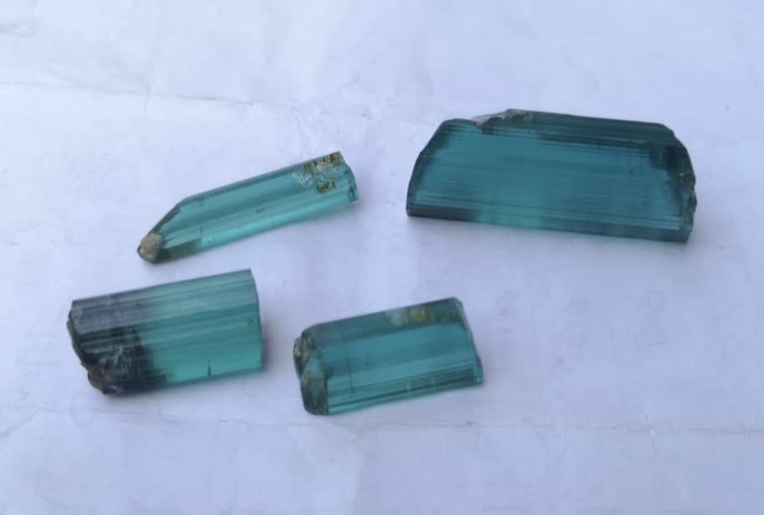 Four rough Ethiopian tourmaline crystals on a light surface